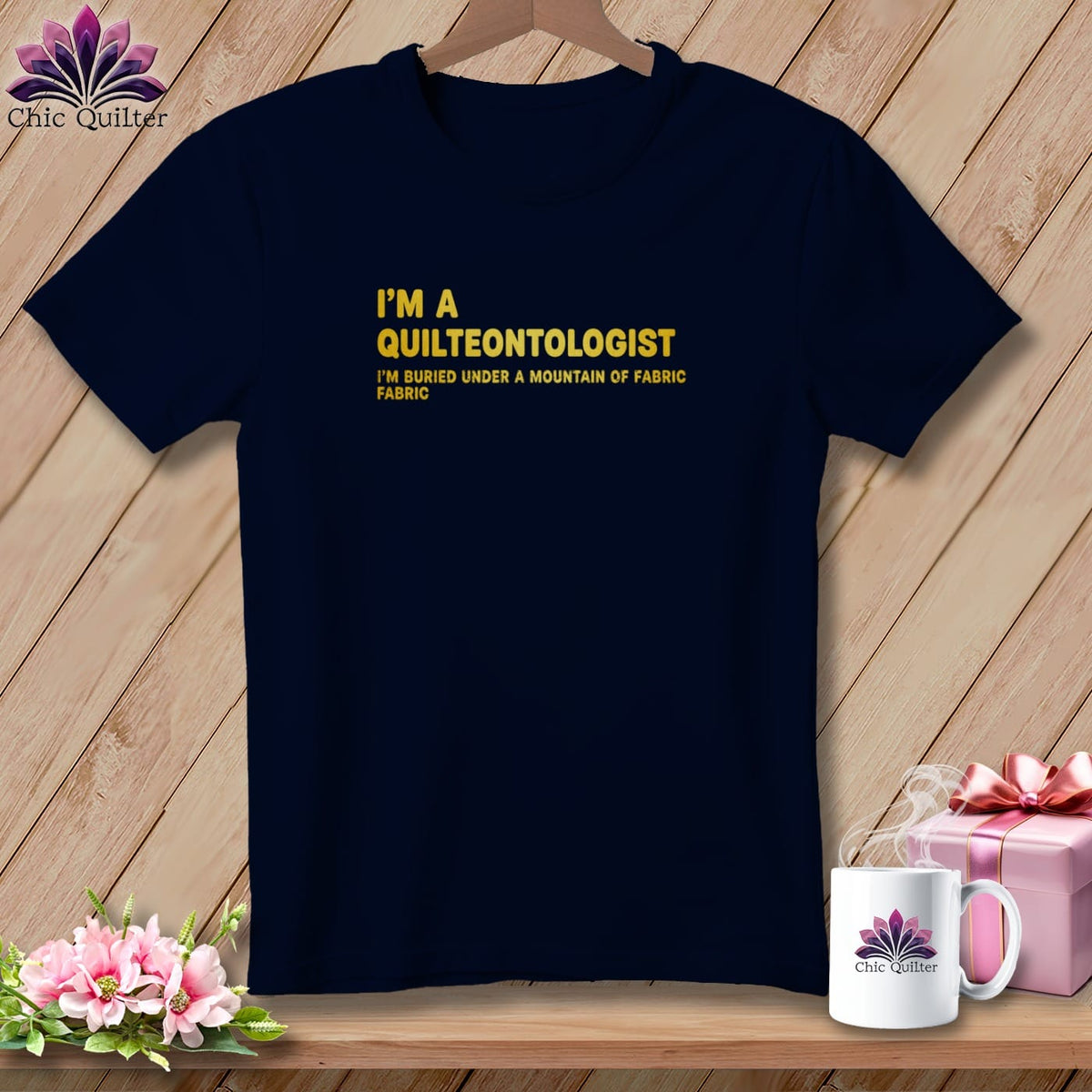 Navy t-shirt with yellow text reading "I'M A QUILTEONTOLOGIST I'M BURIED UNDER A MOUNTAIN OF FABRIC".