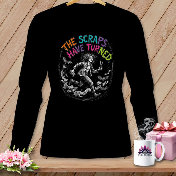 Black t-shirt with a circular graphic of a woman running, holding scissors, with text "THE SCRAPS HAVE TURNED".