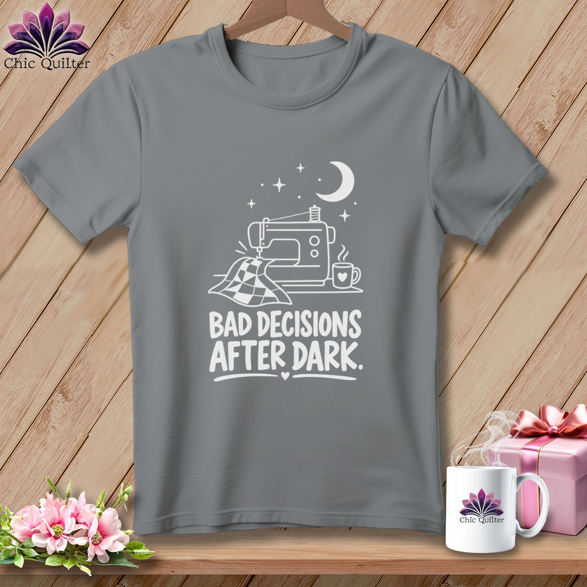 Gray t-shirt with white graphic of sewing machine, fabric, moon, and text "BAD DECISIONS AFTER DARK."