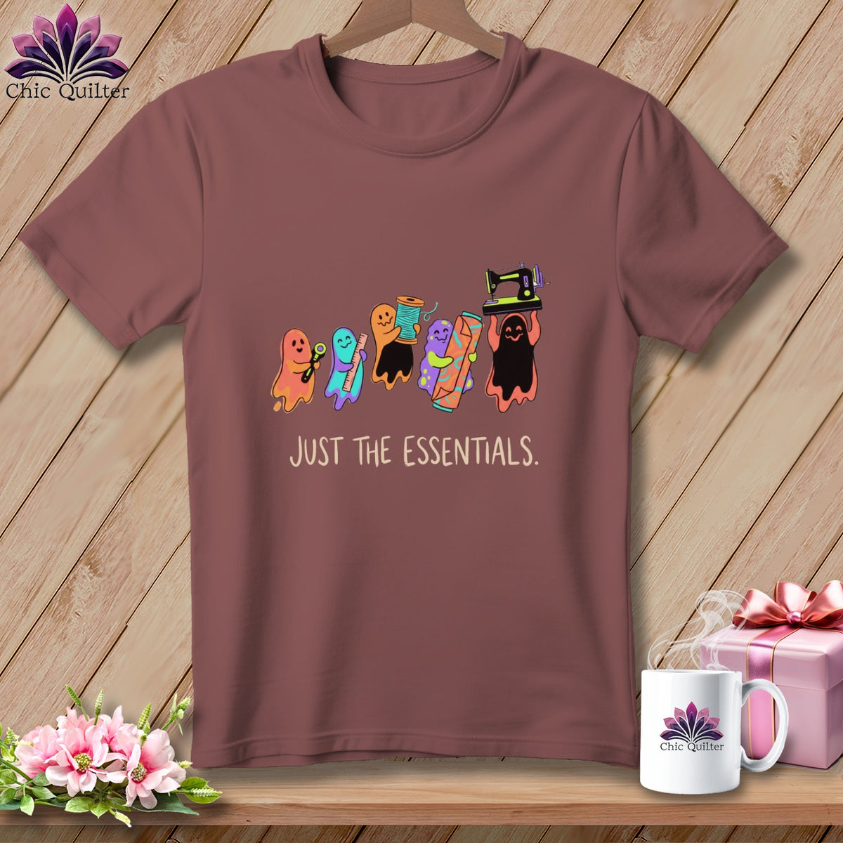 T-shirt with colorful sewing ghosts holding scissors, thread, ruler, fabric, and sewing machine. Text reads "JUST THE ESSENTIALS."