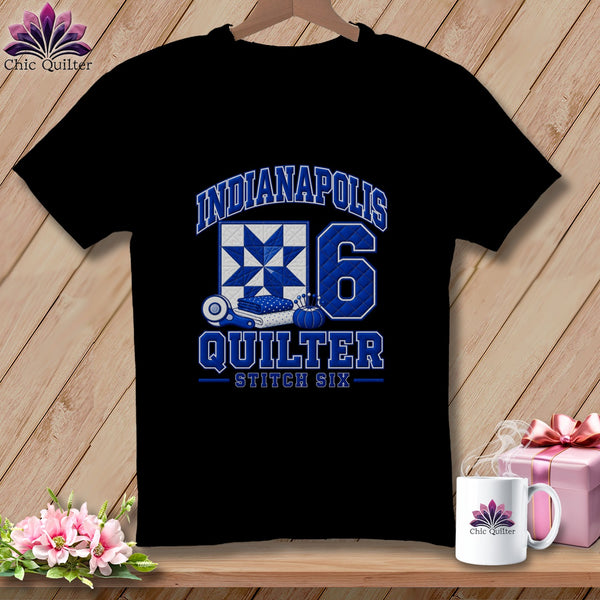 A black t-shirt features blue text reading Indianapolis Quilter Stitch Six, a quilt block, and the number six.