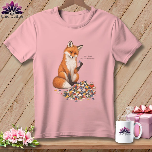 Pink t-shirt with a fox holding a patchwork triangle, text "I MAY HAVE OVERCOMMITTED."