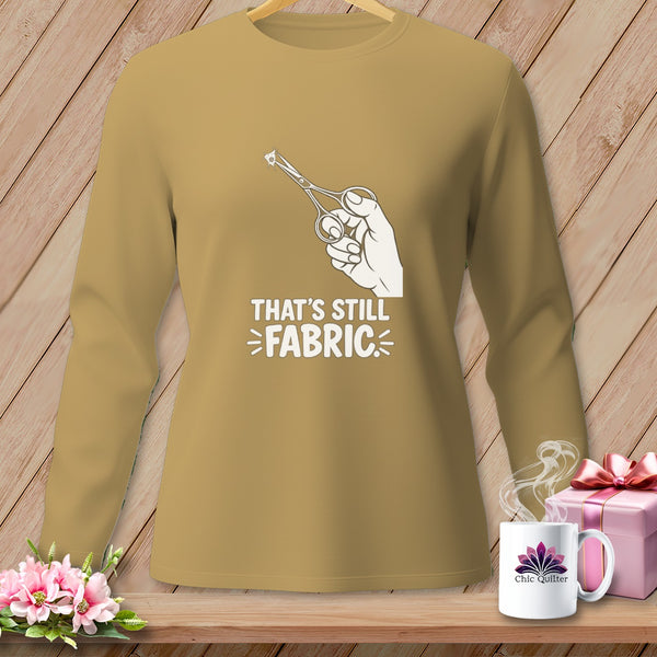 Long-sleeved shirt with hand holding scissors cutting fabric graphic and text "That's Still Fabric".