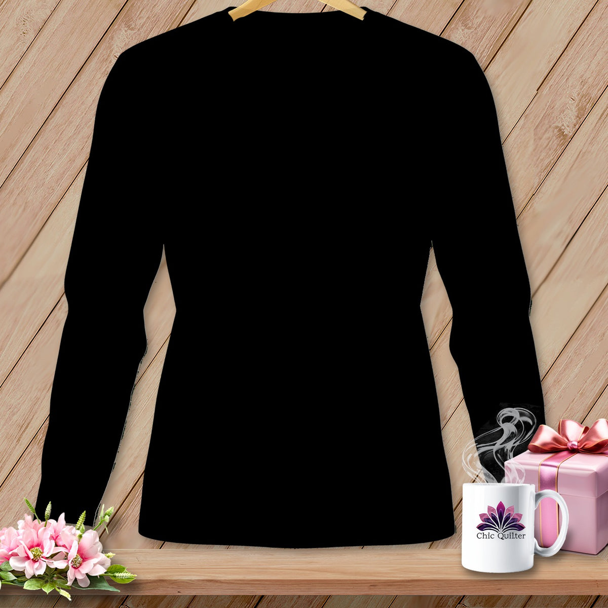Black long sleeve shirt on hanger with mug, gift box, and flowers.