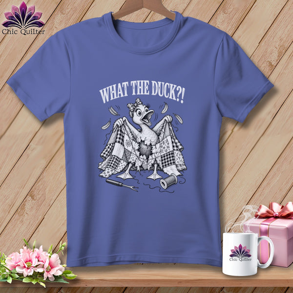 A periwinkle t-shirt with a humorous graphic of a duck wrapped in a tattered patchwork quilt, featuring the text "WHAT THE DUCK?!".