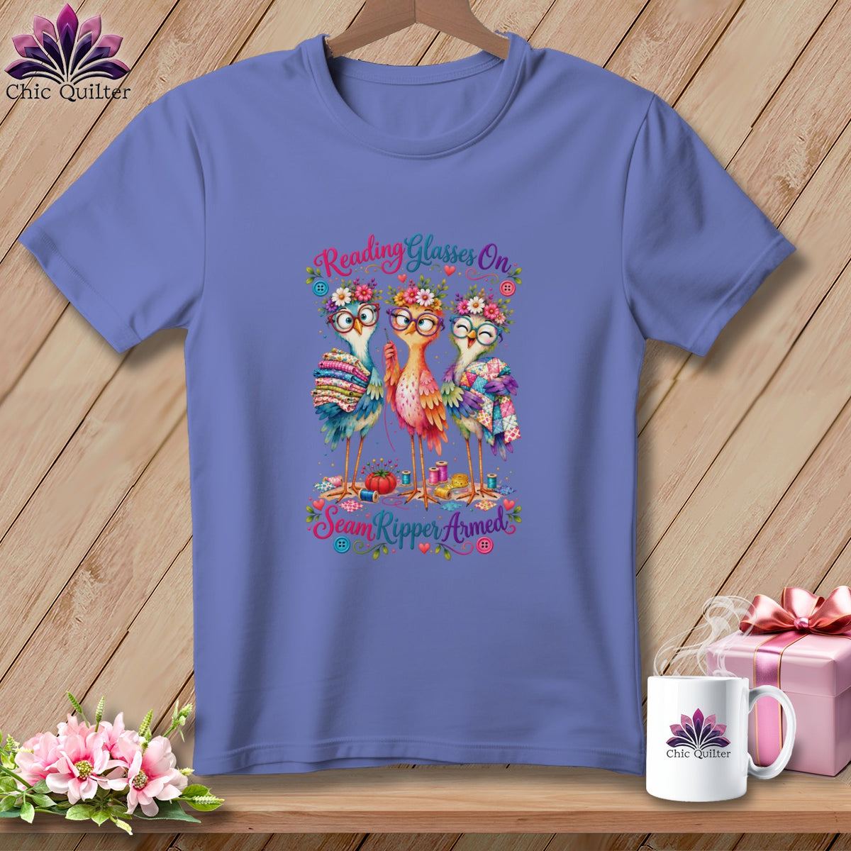 Periwinkle t-shirt featuring three whimsical birds wearing glasses and flower crowns, with sewing-themed text.