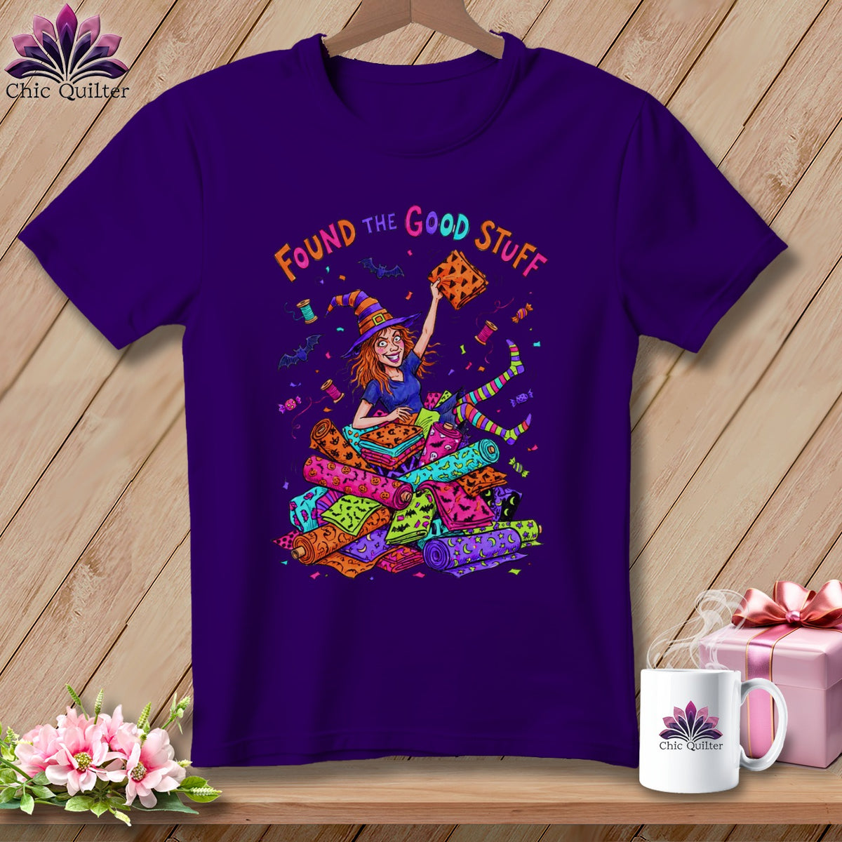 Purple t-shirt with cartoon witch surrounded by Halloween fabric rolls and text "FOUND THE GOOD STUFF".