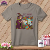 T-shirt with witch holding a flashlight on a colorful patchwork blanket with a ghost.