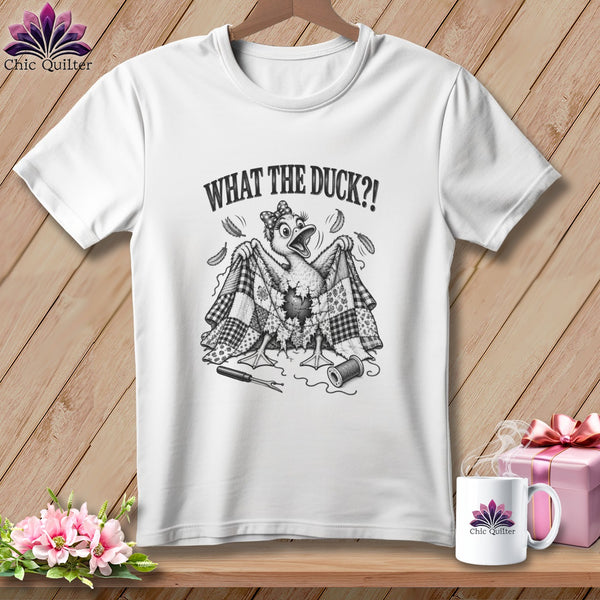 A white t-shirt featuring a cartoon duck holding up a torn patchwork quilt with the text WHAT THE DUCK?!