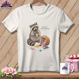 White t-shirt graphic with raccoon and sewing supplies, text reads 