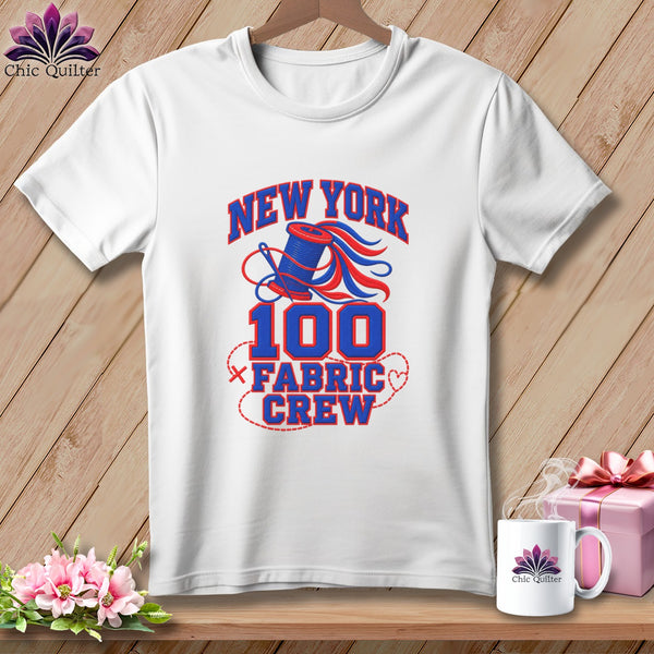 A white t-shirt on a wooden background with text reading New York 100 Fabric Crew.
