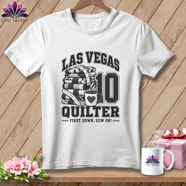 White crewneck t-shirt featuring a Las Vegas Quilter design with a stack of quilts and coffee cup.