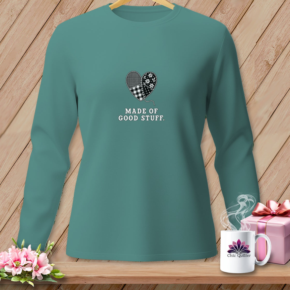 Teal long-sleeve shirt with patchwork heart graphic and "Made of Good Stuff" text.