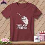 Maroon t-shirt with white graphic of a hand holding scissors cutting fabric.