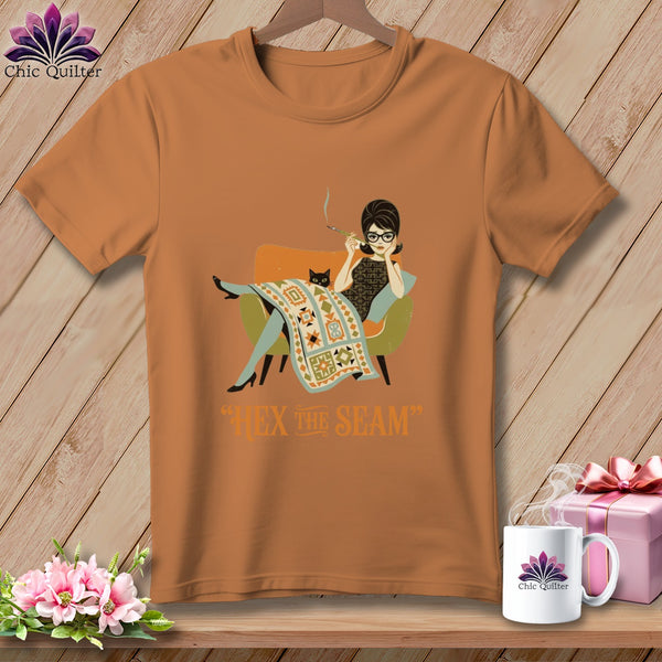 Orange t-shirt with graphic of woman smoking and cat under quilt, text "Hex the Seam".