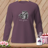 Purple long-sleeve shirt with a drawing of an armchair, quilt, and mug with 