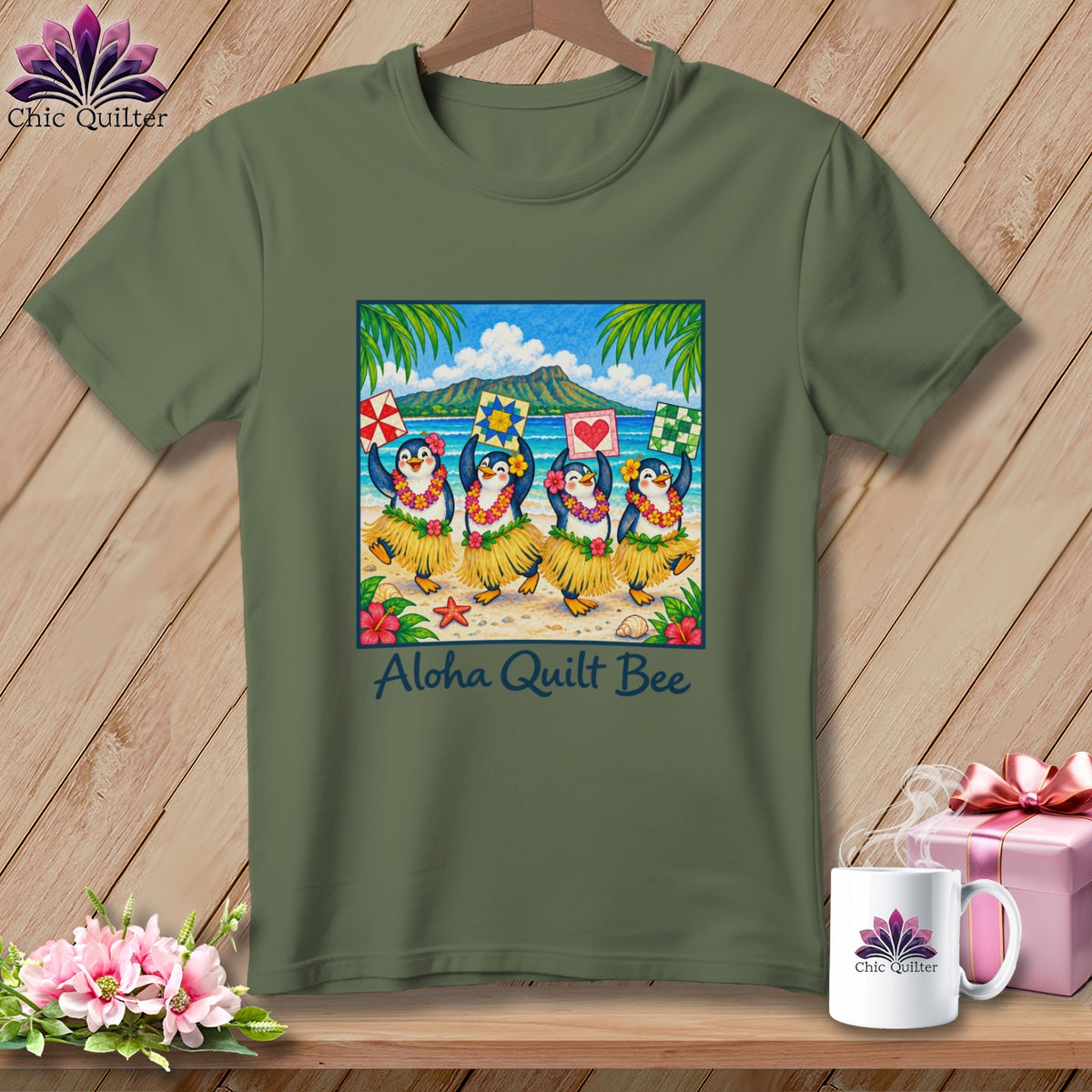 Olive green t-shirt featuring a graphic of four hula-dancing penguins on a beach, with the text Aloha Quilt Bee.