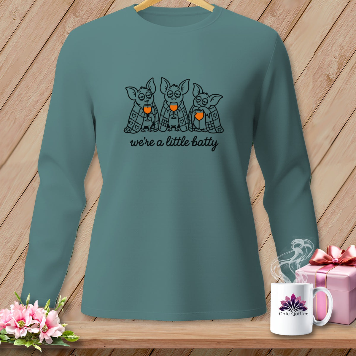 Teal long-sleeve shirt with three cartoon bats drinking from glasses, saying "we're a little batty".