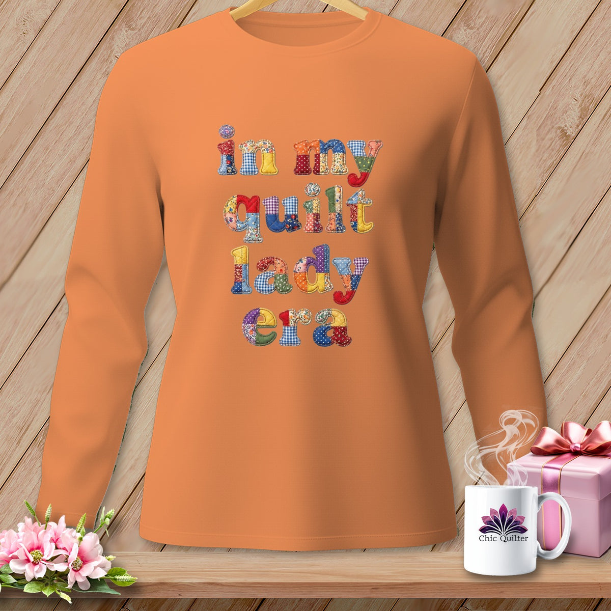 Orange long-sleeve shirt with "in my quilt lady era" text in colorful patchwork lettering.
