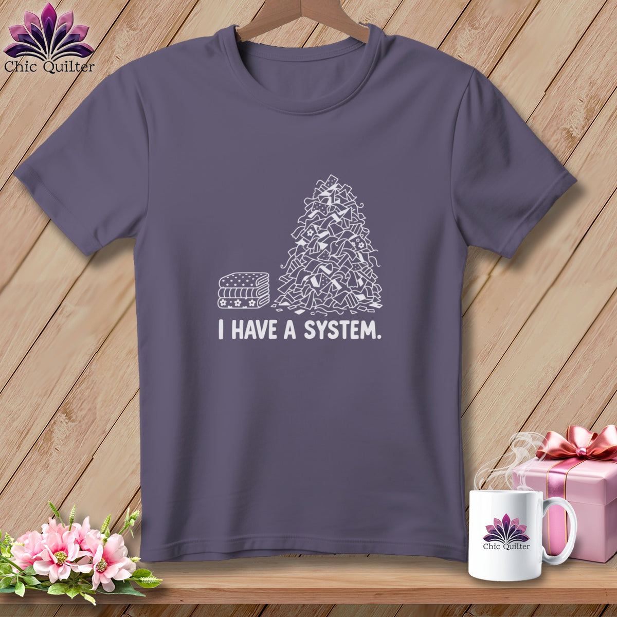 Purple t-shirt with a drawing of neatly folded fabric and a pile of fabric scraps with "I HAVE A SYSTEM."