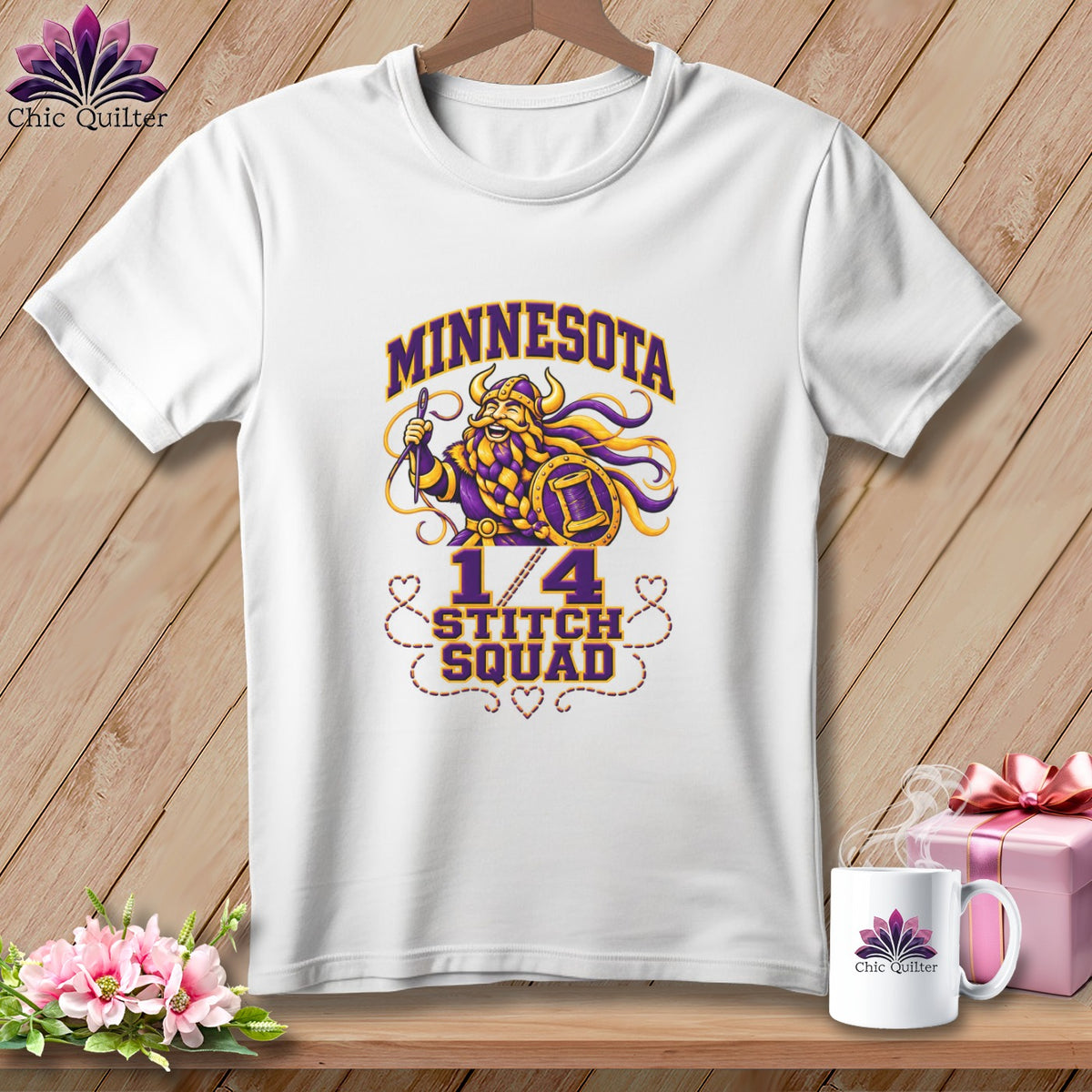 A white t-shirt hanging on a wooden background, featuring a graphic with a Viking and the text Minnesota Stitch Squad.