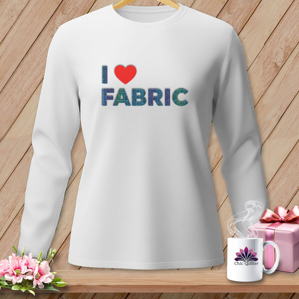 White long-sleeve shirt with text "I ❤️ FABRIC" on a wooden background.