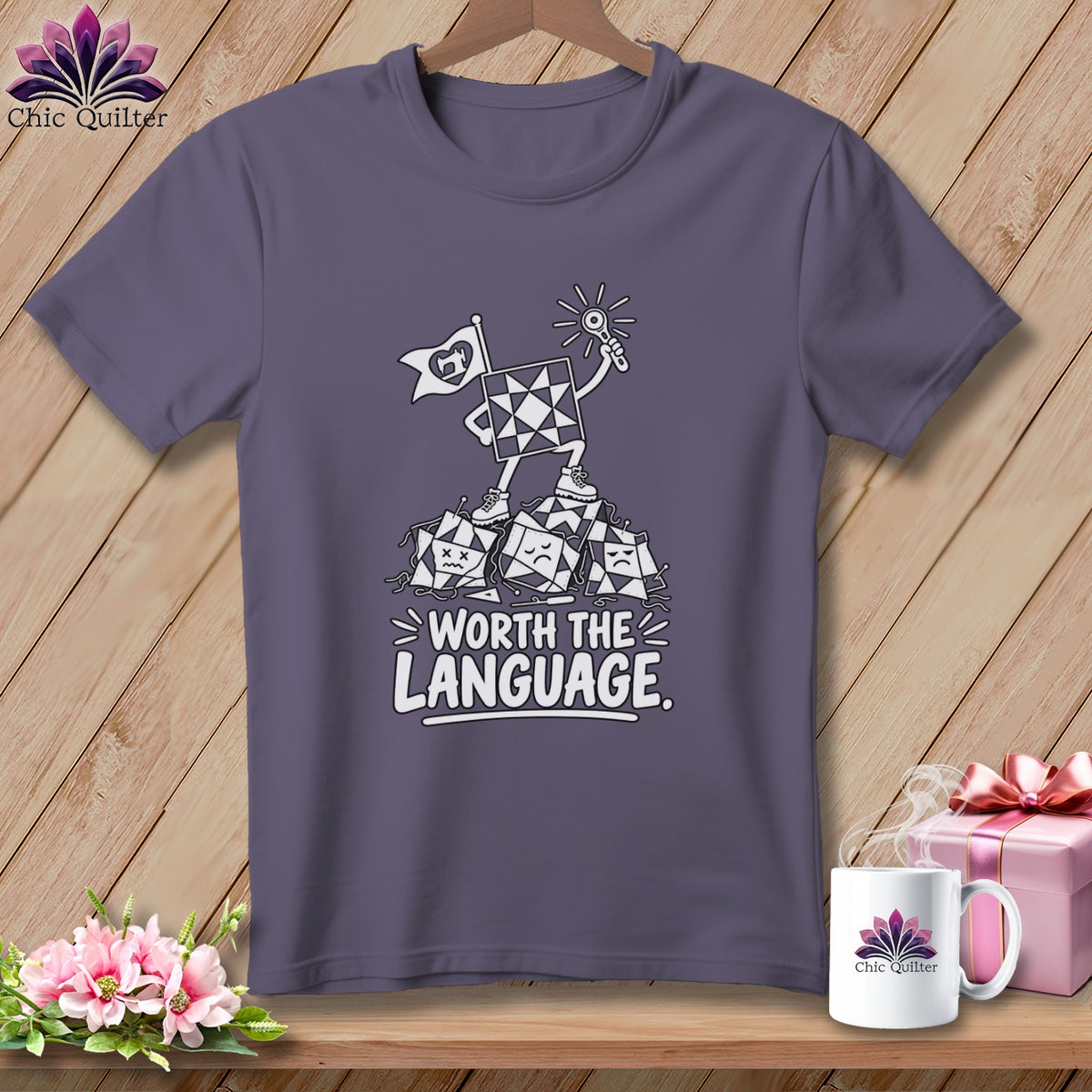 Purple t-shirt with graphic of quilt square character on pile of quilt squares, text "WORTH THE LANGUAGE".
