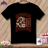 A black t-shirt featuring a graphic with a stack of quilts, a measuring tape, coffee cup, and Cincinnati Quilter text.