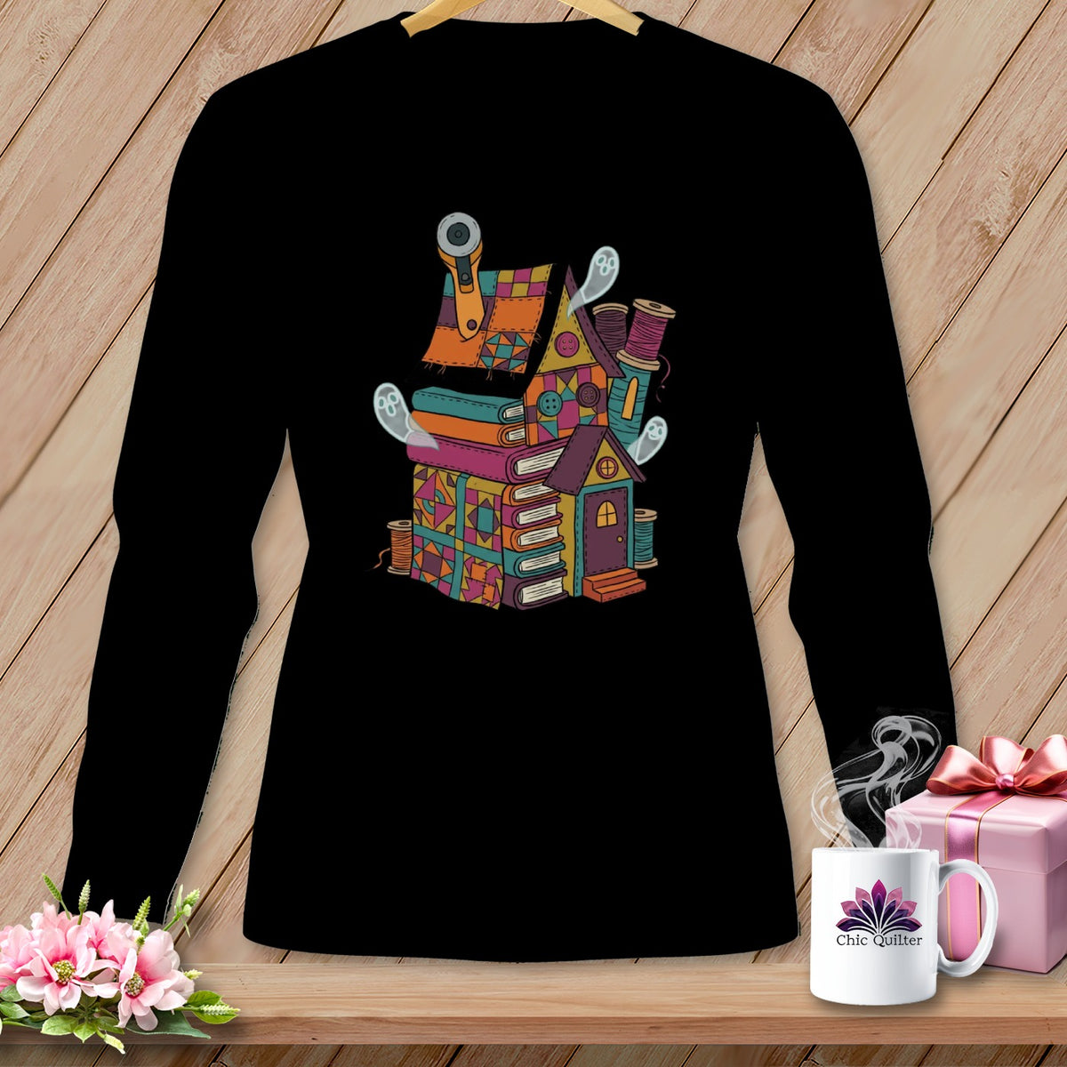 Quilting house illustration with books, thread, and ghosts on a black long-sleeve shirt.