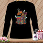 Quilting house illustration with books, thread, and ghosts on a black long-sleeve shirt.