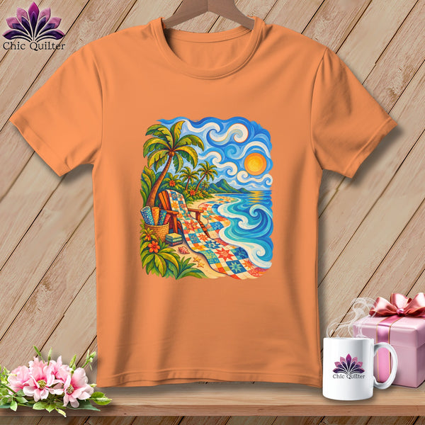 An orange short-sleeved t-shirt hangs against a wooden wall, featuring a colorful tropical beach scene with a quilt-patterned beach blanket.