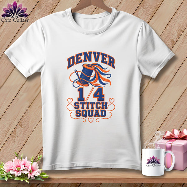 White t-shirt with a blue and orange Denver 1/4 Stitch Squad sewing graphic hanging on wooden background.