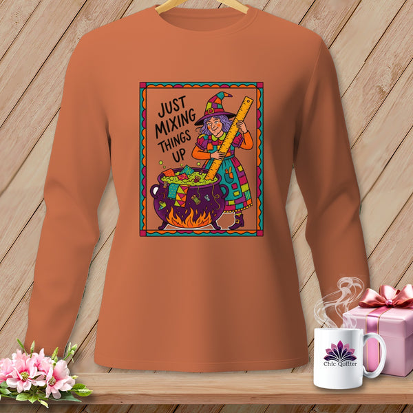 Orange long-sleeve shirt with a witch mixing a cauldron, text says "JUST MIXING THINGS UP".