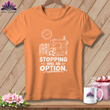 Orange t-shirt with sewing machine, fabric stack, and text 