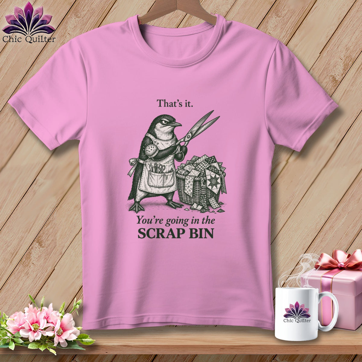 Pink t-shirt with drawing of a penguin holding scissors over a basket of fabric scraps.