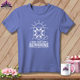Purple t-shirt with white graphic of a quilt block, sun, and needle. Text reads 