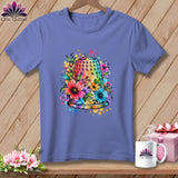 Periwinkle t-shirt with a colorful watercolor thimble graphic surrounded by flowers on a wooden background.