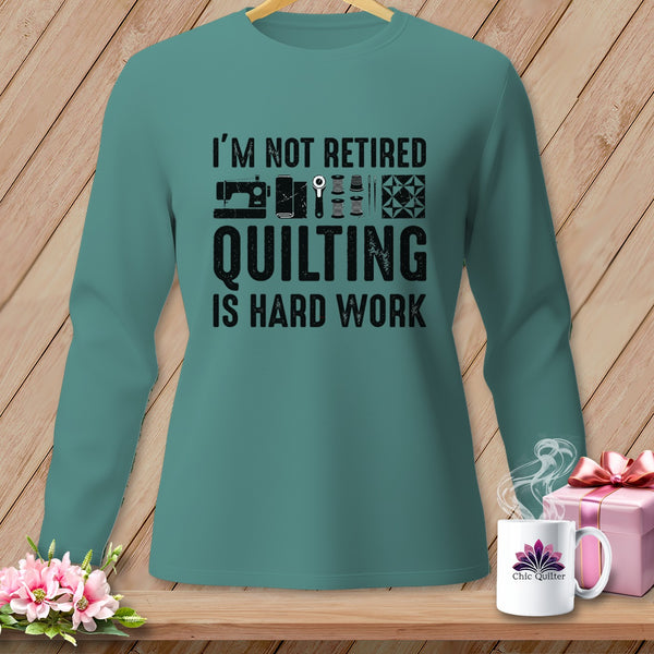 Teal long-sleeve shirt with "I'm not retired quilting is hard work" text and sewing graphics.