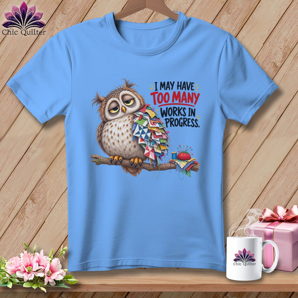 Light blue t-shirt with an owl wearing a quilt and text reading "I MAY HAVE TOO MANY WORKS IN PROGRESS."