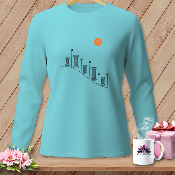 Turquoise long-sleeve shirt with sewing spool graphic and orange button.