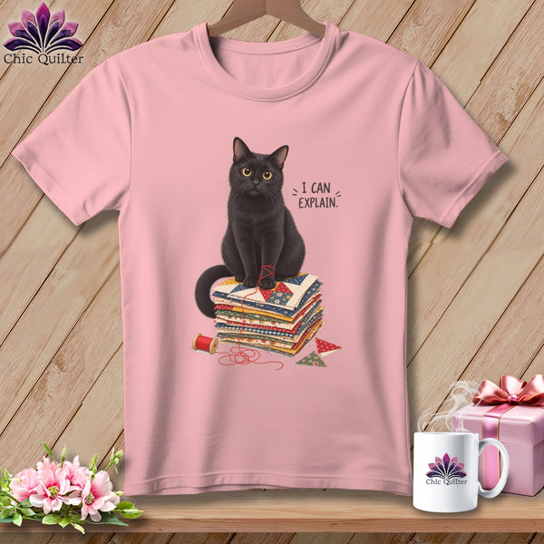 Black cat sitting on fabric scraps with text "I CAN EXPLAIN."