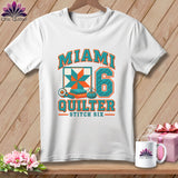 A white t-shirt features a colorful graphic with the text Miami Quilter Stitch Six, a quilt block, and the number six.