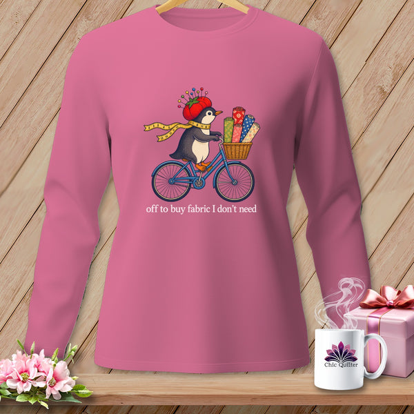 Pink long-sleeve shirt with penguin on bike, carrying fabric, and text "off to buy fabric I don't need".