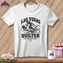 A white t-shirt on a wooden background features a graphic of a bird holding a spool of thread with the text "Las Vegas Quilter."