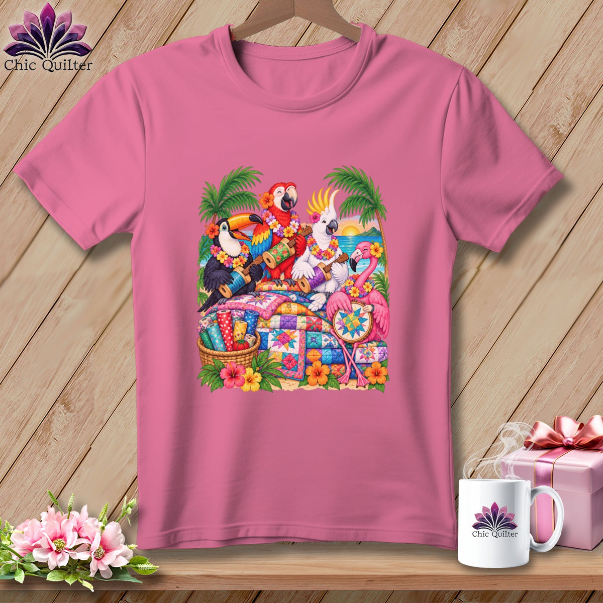 A pink t-shirt displays a graphic of tropical birds playing instruments and quilting on a beach.