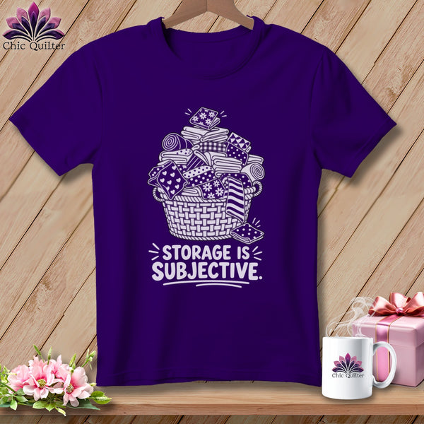 Purple t-shirt with white graphic of fabric rolls in a basket and "STORAGE IS SUBJECTIVE" text.