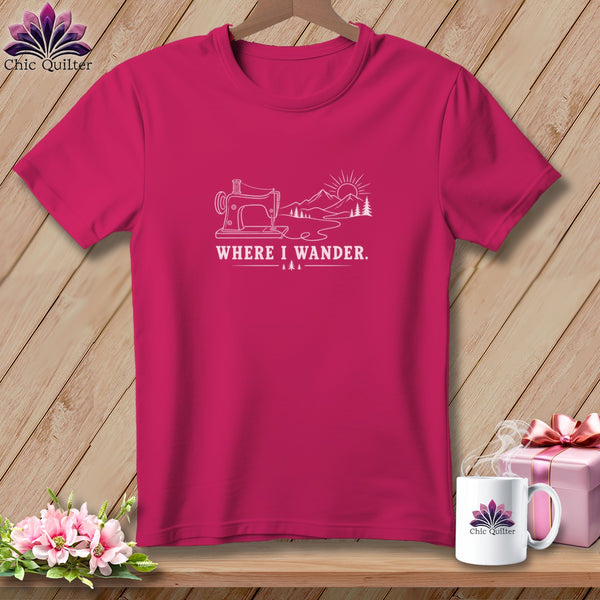 Pink t-shirt with line art of sewing machine, mountains, sun, and trees. Text reads "WHERE I WANDER."