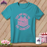 Teal t-shirt featuring pink text that reads Stop and Smell the Fat Quarters and a wrapped stack of fabric.