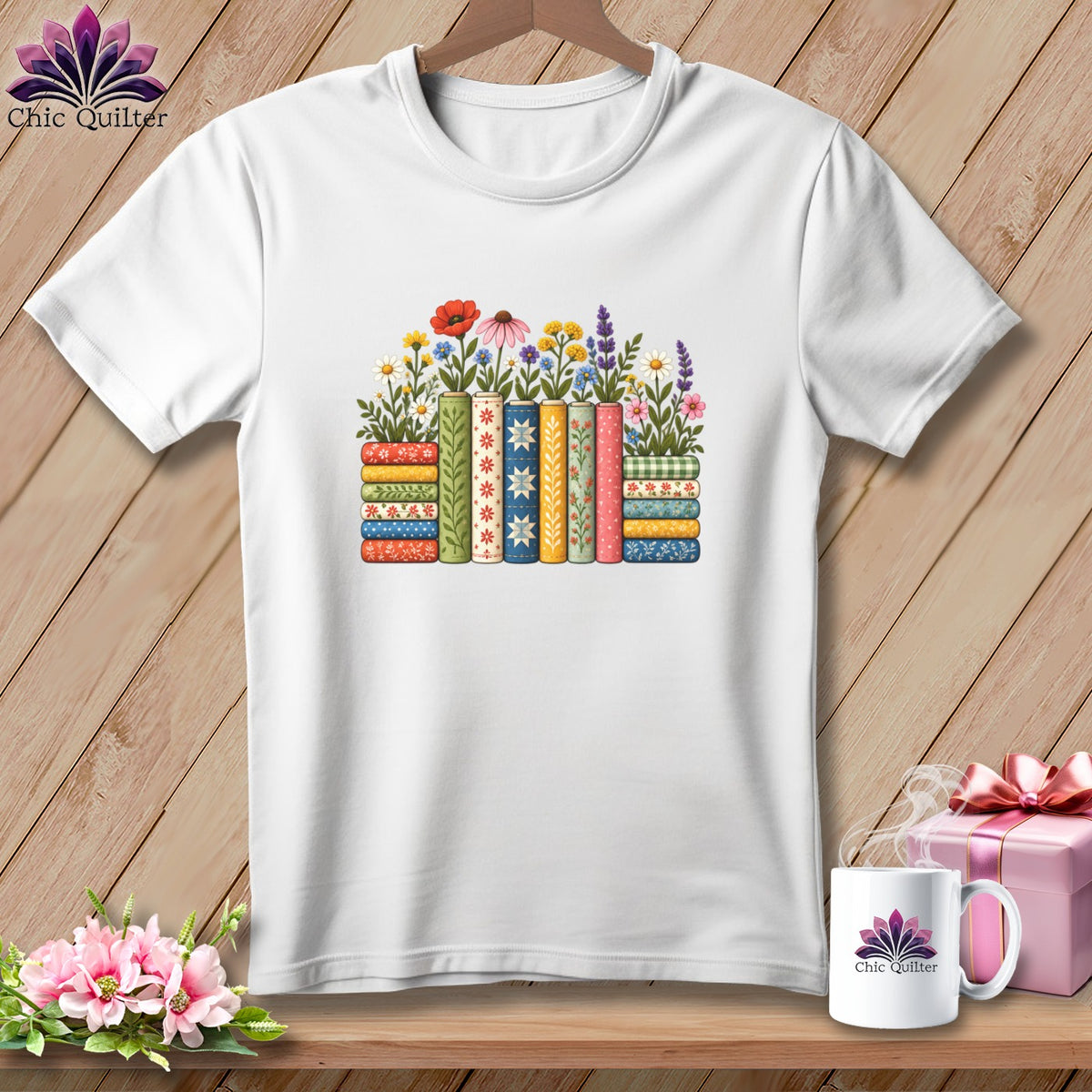 White t-shirt featuring a colorful graphic of stacked books adorned with flowers on a wooden background.