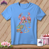 Light blue t-shirt with two flamingos sewing with fabric, rotary cutter, and pins.